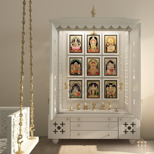 A solid wood mandir with pure brass bells, Tanjore art prints, cutwork designs and storage, tinted in a snow-white color