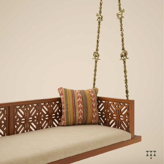 A handcrafted wooden swing with a cutwork pattern, tinted in almond brown with a decorative brass chain with animal motifs
