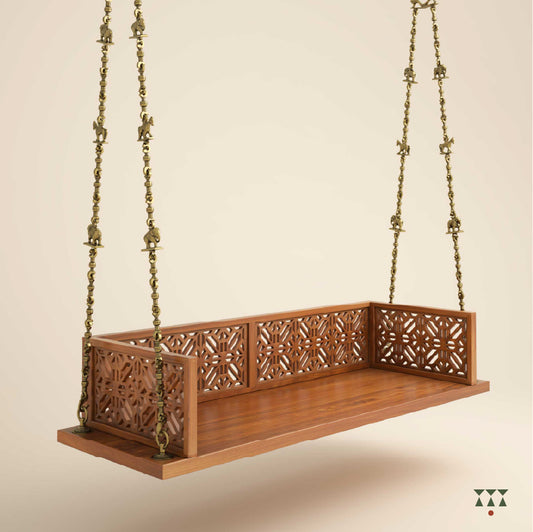 A handcrafted wooden swing with a cutwork pattern, tinted in almond brown with a decorative brass chain with animal motifs