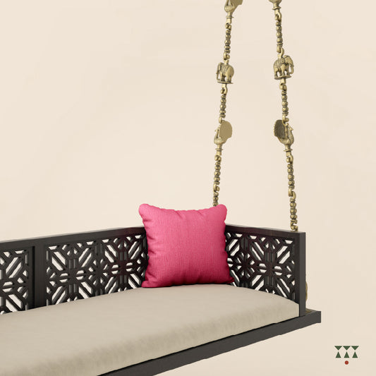 A wooden swing with cutwork, tinted in slate black with a decorative brass chain and animal motifs, fabric seat and cushions