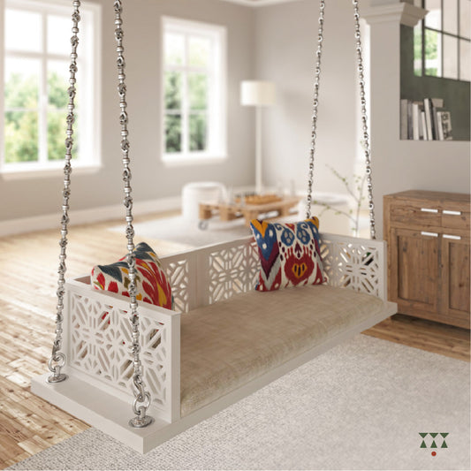A handcrafted wooden swing with cutwork, tinted in snow white with a decorative brass chain in a sliver finish