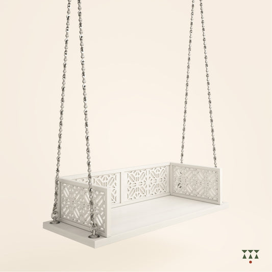 A handcrafted wooden swing with cutwork, tinted in snow white with a decorative brass chain in a sliver finish