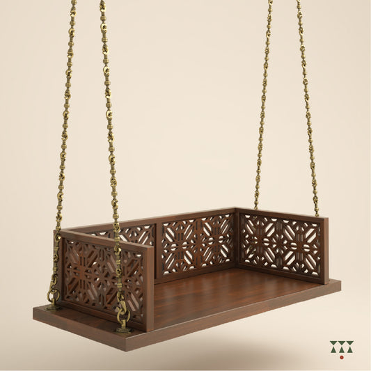A handcrafted wooden swing with cutwork, tinted in tamarind brown with a decorative brass chain