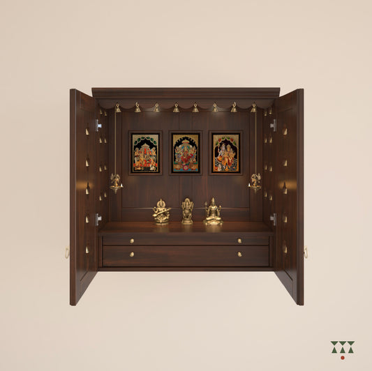 A solid wood mandir with pure brass bells, framed art prints, cutwork designs and storage, tinted in tamarind brown