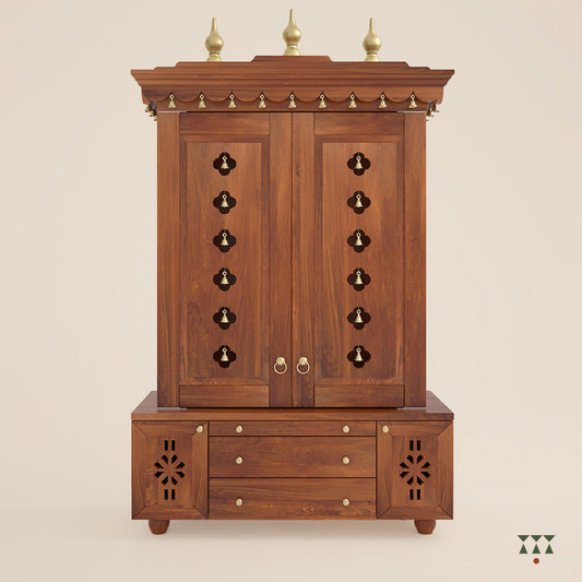 A solid wood mandir with doors, pure brass bells, accessories, cutwork designs and storage, tinted in an almond brown color