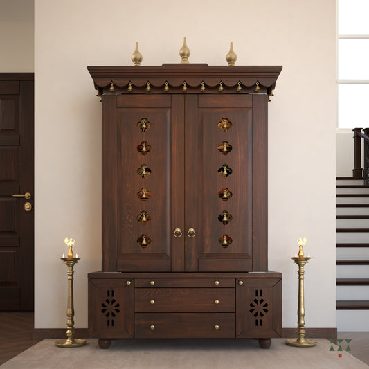 A solid wood mandir with doors, pure brass bells, accessories, cutwork designs and storage, tinted in a tamarind brown color