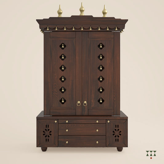 A solid wood mandir with doors, pure brass bells, accessories, cutwork designs and storage, tinted in a tamarind brown color