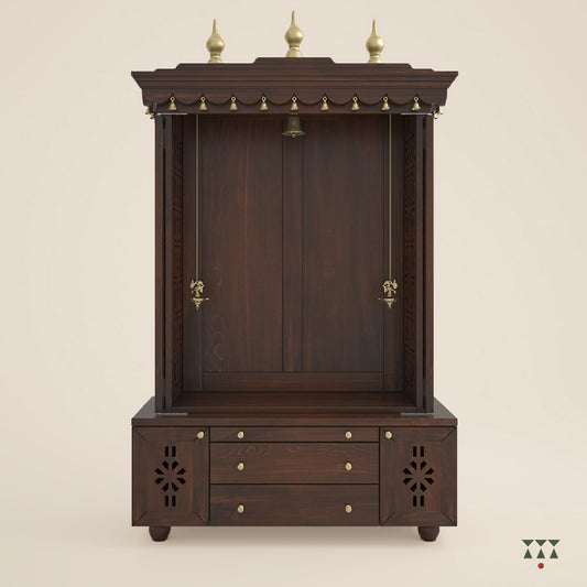 A solid wood mandir with pure brass bells, accessories, cutwork designs and storage, tinted in a tamarind brown color