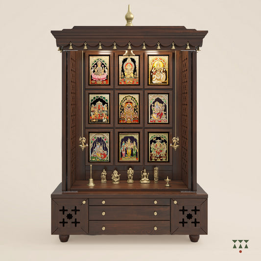 A solid wood mandir with pure brass bells, Tanjore art prints, cutwork designs and storage, tinted in a tamarind brown color