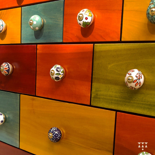 Colorful drawers of a chest of drawer with handmade ceramic knobs