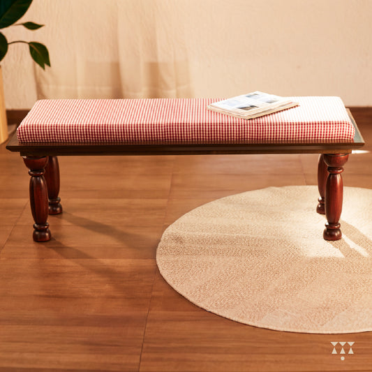 A handcrafted wooden bench with turned legs and a cushioned seat, upholstered in a luxurious checked silk
