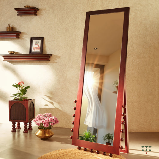 A solid wood full length mirror with a stand and textural details at the bottom, in a gradation of purple and red tints