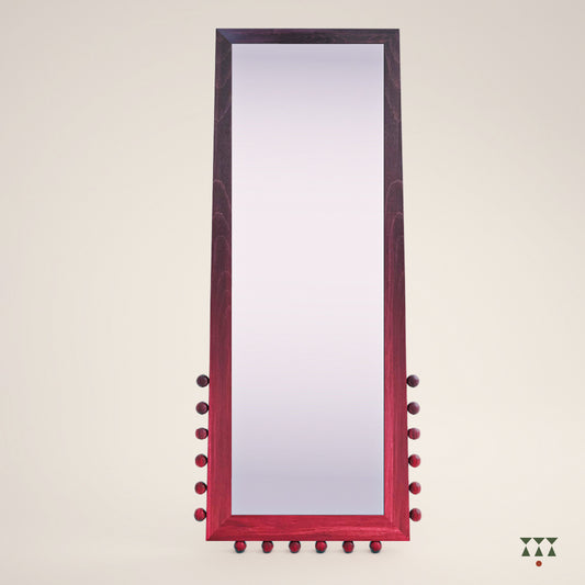 A solid wood full length mirror with a stand and textural details at the bottom, in a gradation of purple and red tints