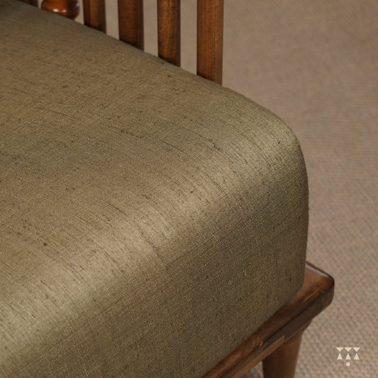 A close up of the colorful, rich silk upholstery of a solid wood statement armchair