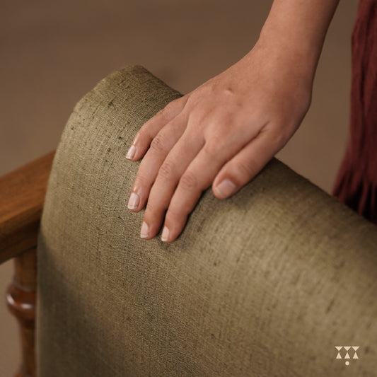 A close up of the colorful, rich silk upholstery of a solid wood statement armchair