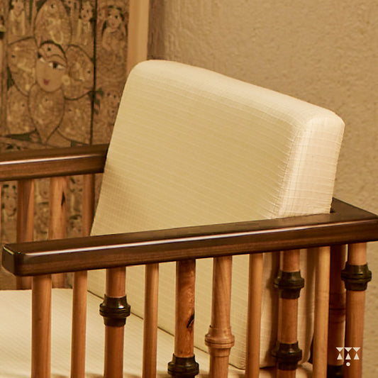 A close up of the textured, white silk upholstery of a solid wood statement armchair