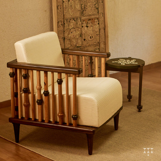 A solid wood statement chair with the arm and backrest made of multiple turned spindles, upholstered in white textured silk