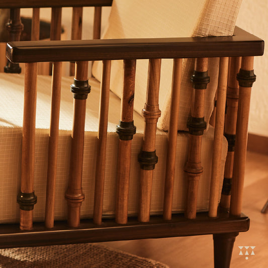 A close up of multiple turned spindles that make the armrest of a solid wood statement armchair