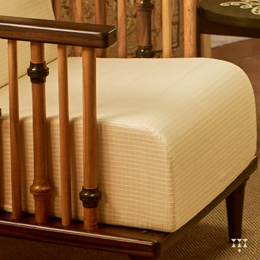 A close up of the textured, white silk upholstery of a solid wood statement armchair