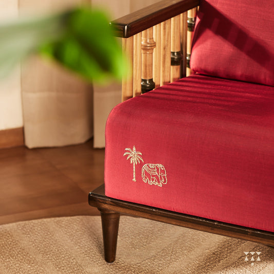 Close up of the embroidered elephant and coconut tree motif on a red silk upholstered solid wood statement armchair