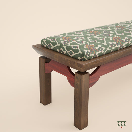 A close up of an artisanal solid wood bench with an upholstered seat in a printed Kilim fabric