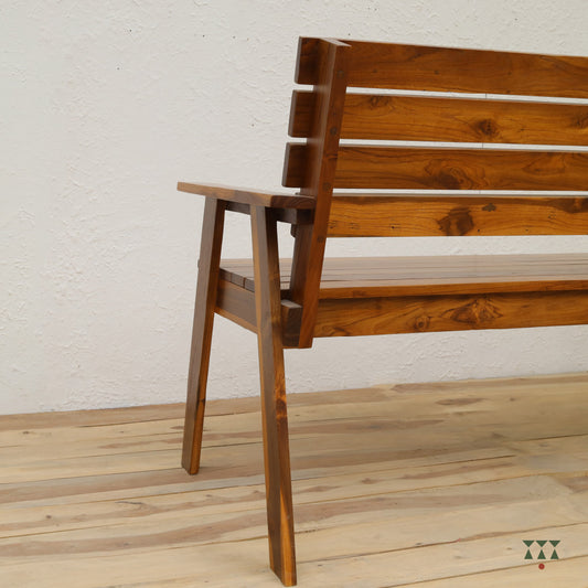 Wooden bench with slatted backrest on a wooden floor against a white wall