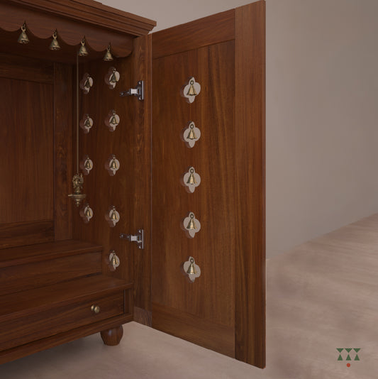 A solid wood mandir with doors, pure brass elements, cutwork designs and storage, tinted in almond brown