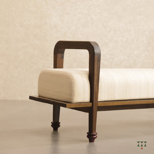 Close up of a sculpted long wooden bench upholstered in beige silk, tinted in Mocha Brown with a Beet Red accent