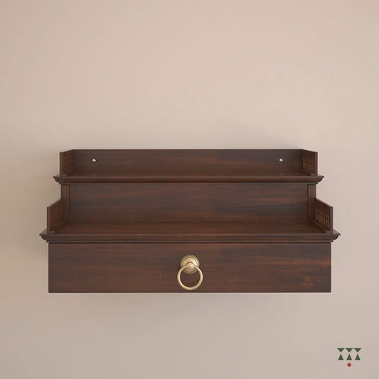A compact wooden, wall mounted Mandir with steps, cutwork, storage and pure brass elements tinted in tamarind brown