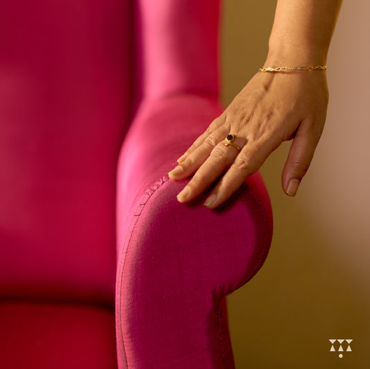 Close up of a solid wood wing chair draped in luxurious magenta silk