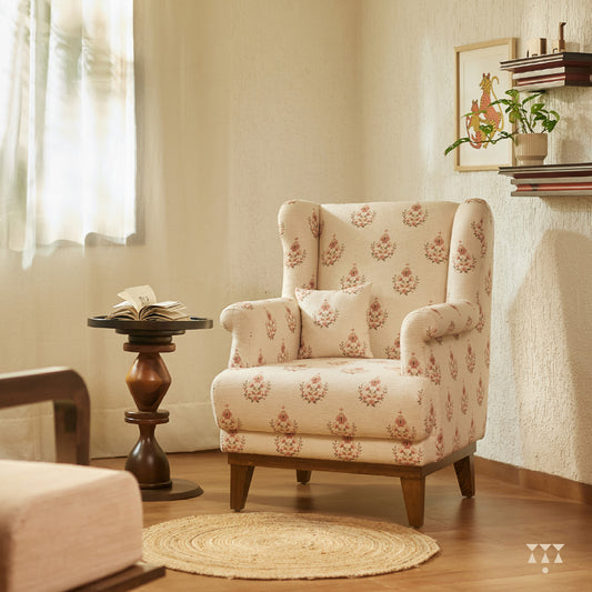 A solid wood wing chair draped in a floral printed white fabric with a matching cushion, tinted in mocha brown