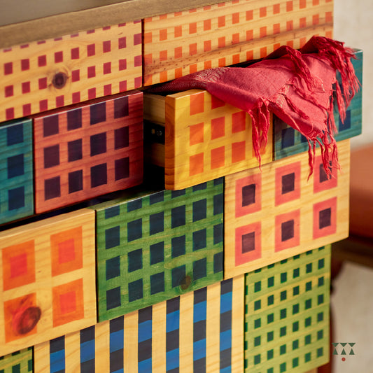 A close up of a chest of drawers with vibrant facade inspired by Madras check textiles, crafted in solid wood