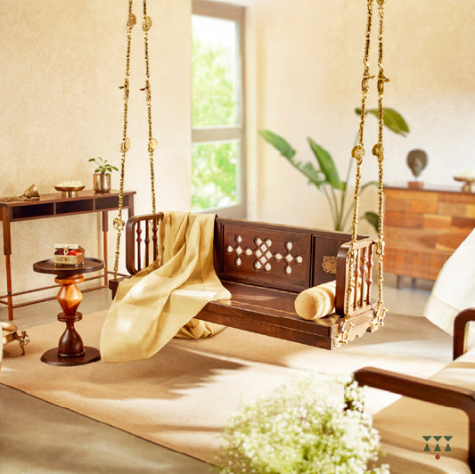A wooden swing crafted with Kolam, Annapakshi and floral designs on the backrest and seat with pure brass animal motif chains