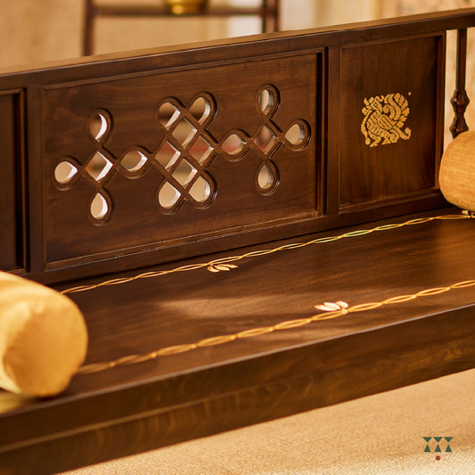 A close up of a wooden swing crafted with Kolam, Annapakshi and floral designs on the backrest and seat