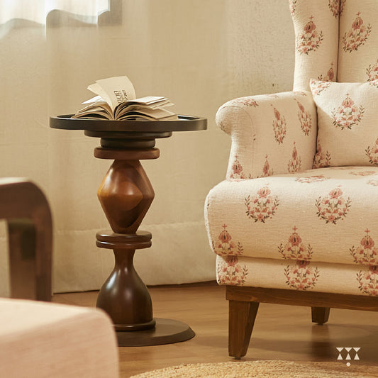 A solid wood side table with a circular top and a sculptural body tinted in Mocha Brown with a Mustard Yellow accent
