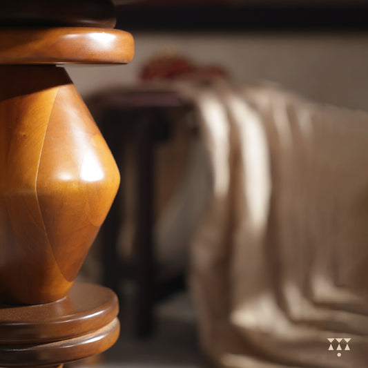 Close up of the sculptural body of a solid wood end table tinted in Mocha Brown with a Mustard Yellow accent