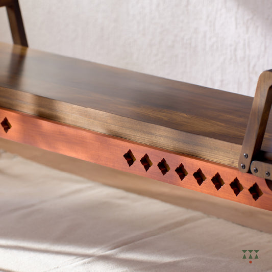 Close up of the sharp geometry and cutwork of a wooden bench, tinted in Mocha Brown with a Saffron Orange accent