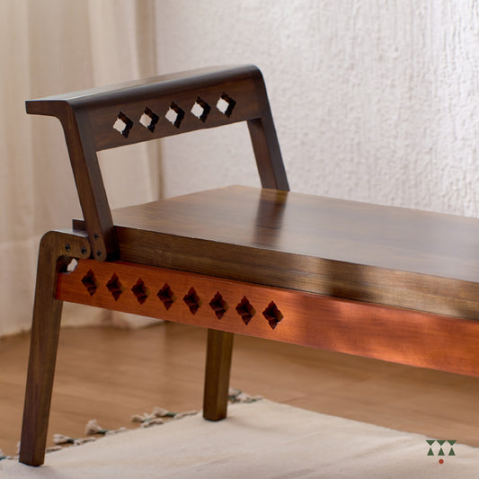 Close up of the sharp geometry and cutwork of a wooden bench, tinted in Mocha Brown with a Saffron Orange accent