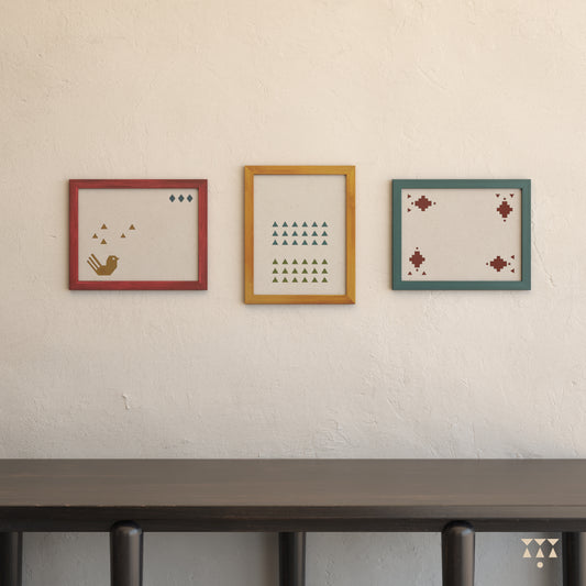 Set of 3 large wooden frames tinted in beet red, lagoon blue & mustard yellow placed on a wall above a console table