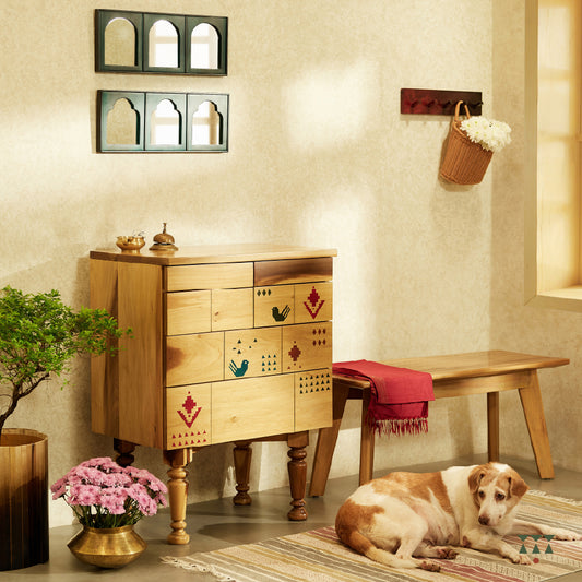 A lifestyle image of a petite chest of drawers handcrafted in solid wood, tinted in Sand Brown with multicolor textile motifs