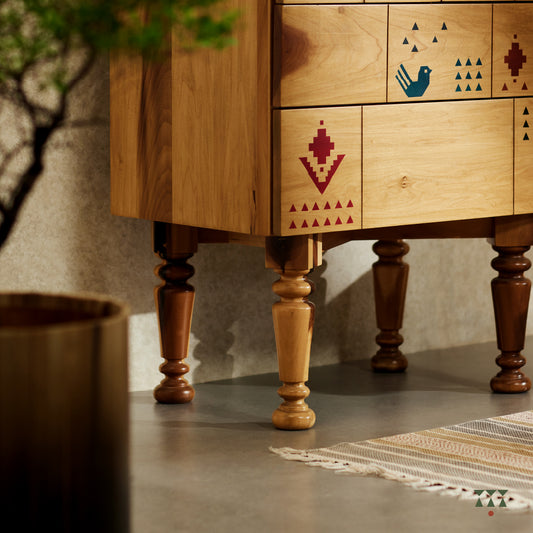 A close up of a petite chest of drawers handcrafted in solid wood, tinted in Sand Brown with multicolor textile motifs