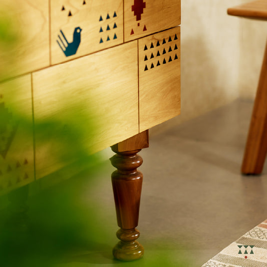 A close up of a petite chest of drawers handcrafted in solid wood, tinted in Sand Brown with multicolor textile motifs