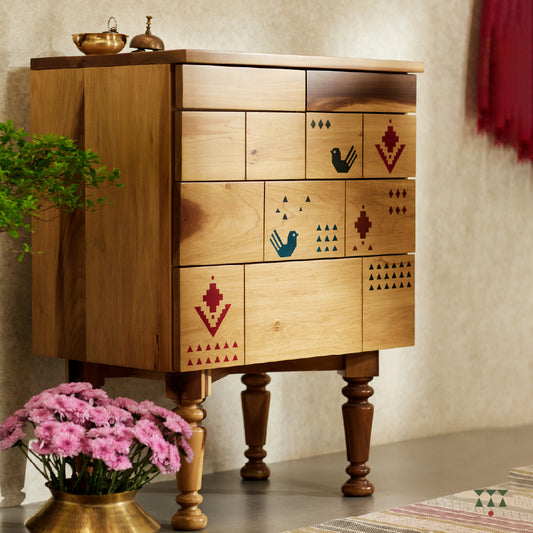 A lifestyle image of a petite chest of drawers handcrafted in solid wood, tinted in Sand Brown with multicolor textile motifs