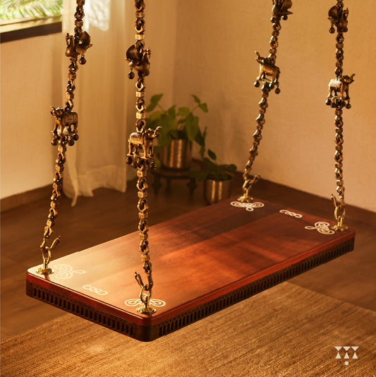A solid wood swing with a pure brass animal motif chain and Kolam patterns inlayed in the seat