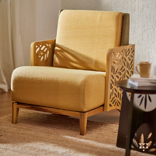 A wooden statement chair with cutwork armrest panels, silk fabric and tinted in Sand Brown with Moringa a green accent