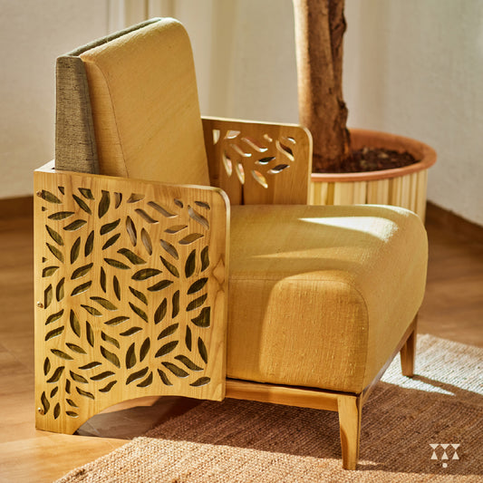 A wooden statement chair with cutwork armrest panels, silk fabric and tinted in Sand Brown with Moringa a green accent
