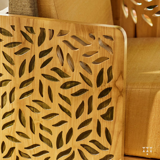Close up of the cutwork armrest panels of a statement armchair, tinted in Sand Brown with a Moringa green accent