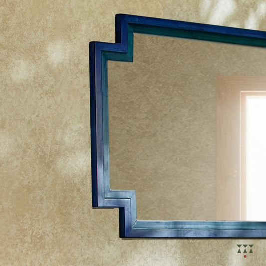 A large wall mirror with unique inverse edges layered with blue accents, handcrafted in solid wood