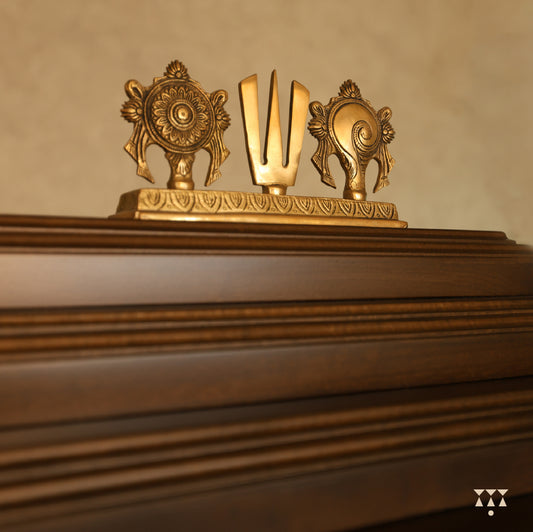 Close up of Vikat temple top showing decorative gold emblem with a trident on a textured surface