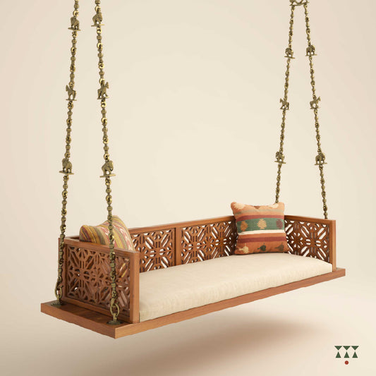 A handcrafted wooden swing with a cutwork pattern, tinted in almond brown with a decorative brass chain with animal motifs